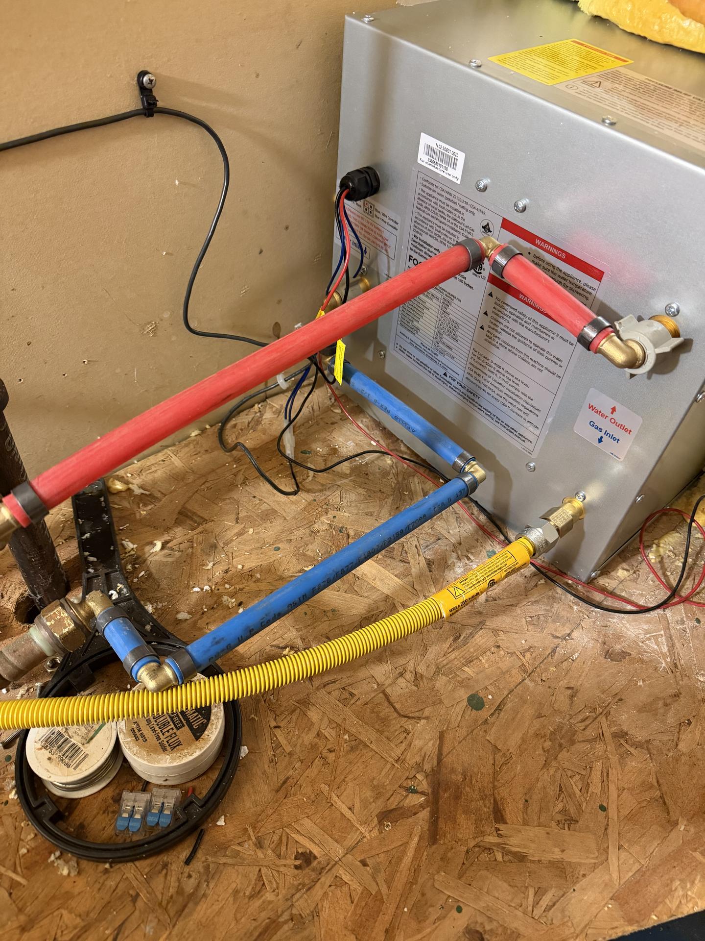 PEX water lines and fittings connected to the back of an RV water heater inside an open access compartment
