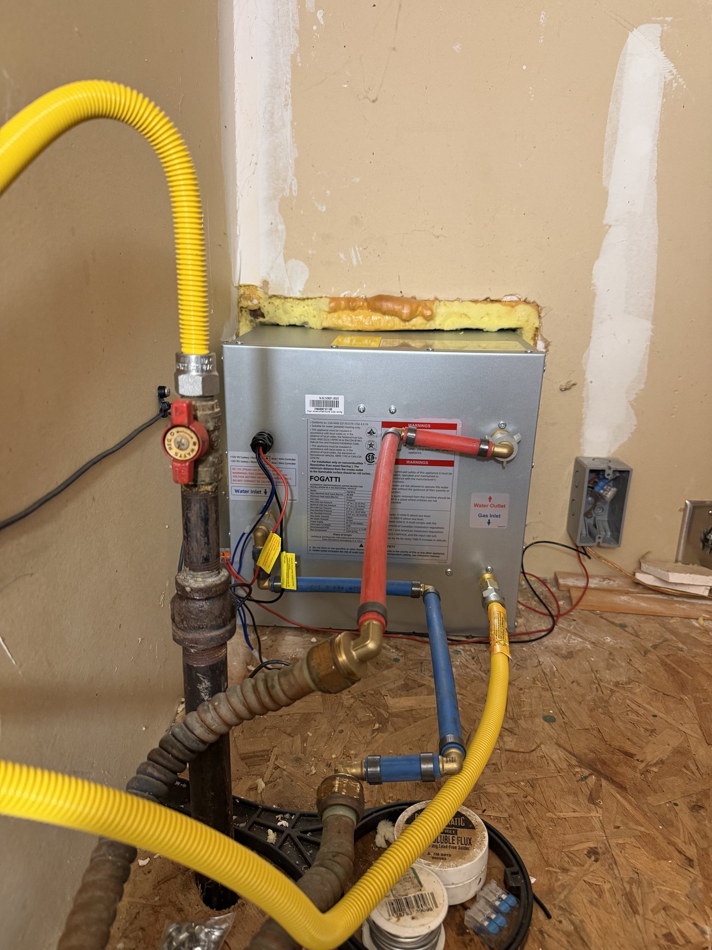 Yellow flexible gas line and shutoff valve connected to an RV tankless water heater during installation
