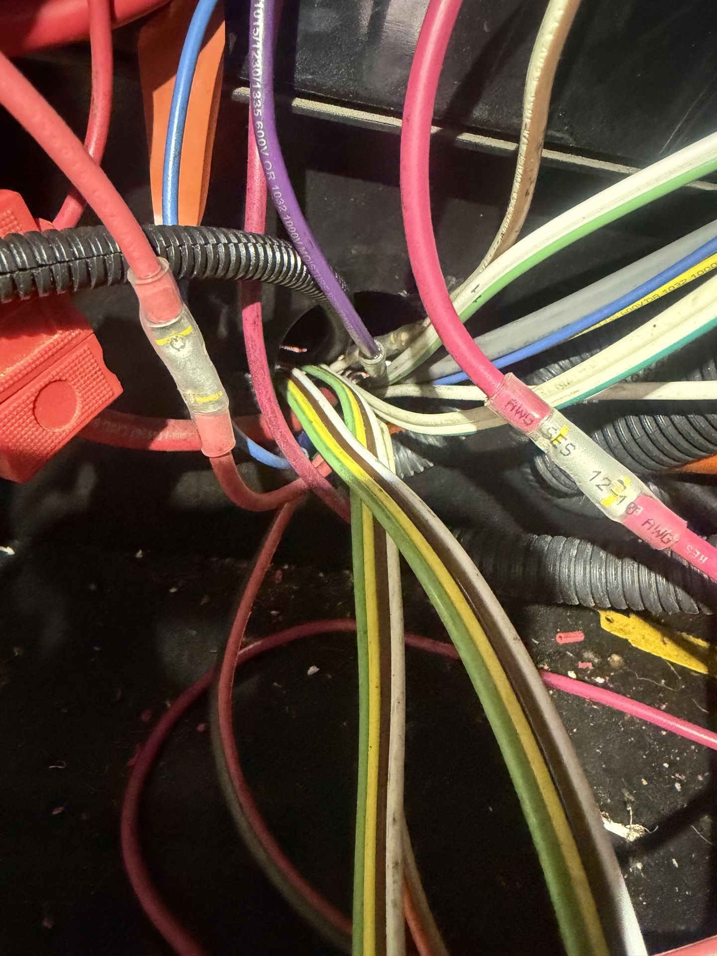 Bundle of colored 12V RV wiring with heat-shrink butt connectors and conduit being traced during electrical troubleshooting