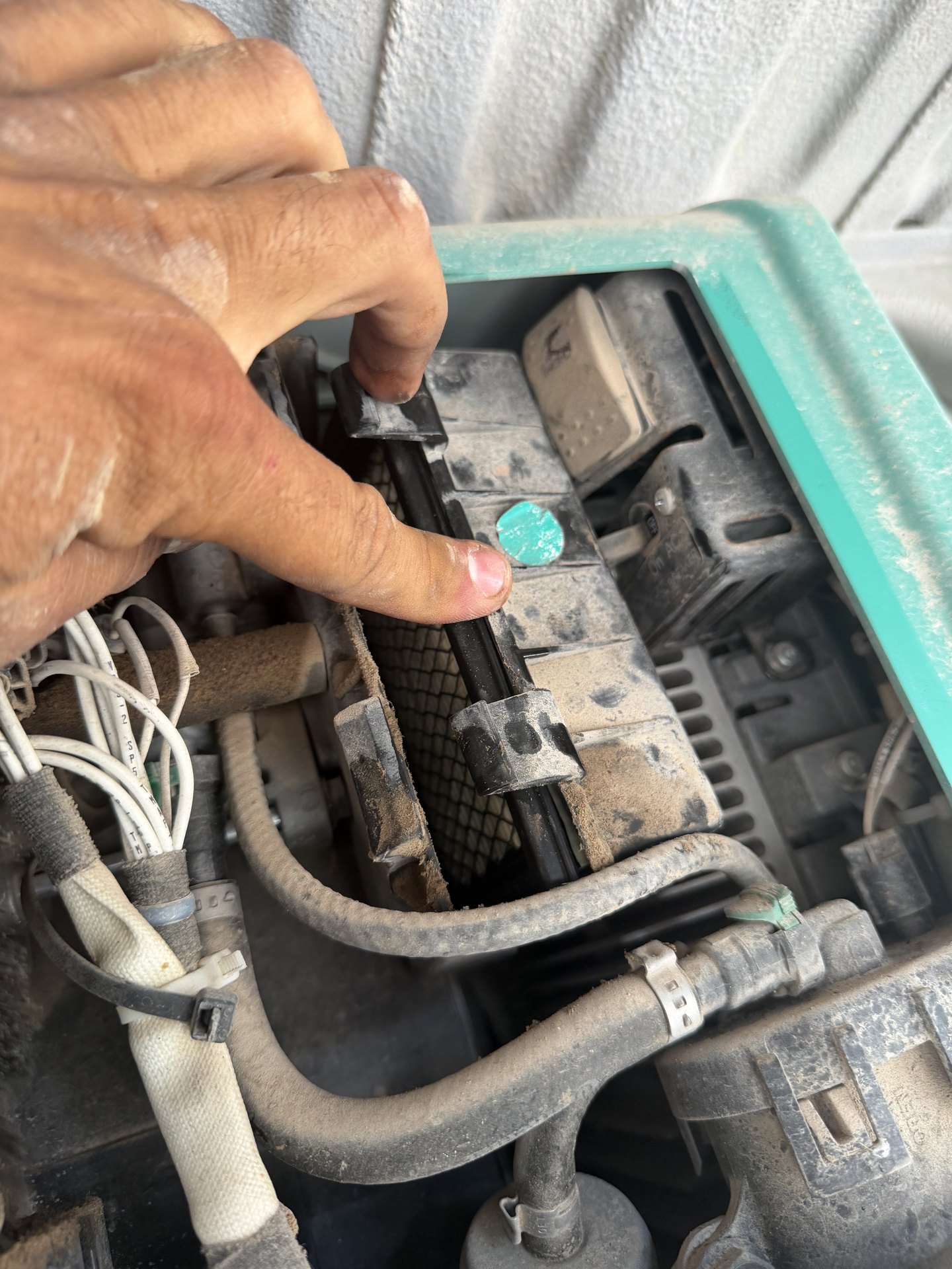 Technician pointing to the dusty air filter and fuel lines inside an open RV generator housing during troubleshooting