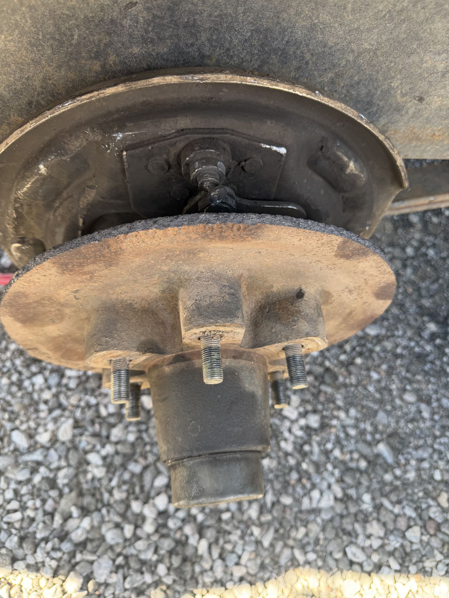Worn RV trailer brake drum and hub pulled away from the backing plate for wear inspection under the coach