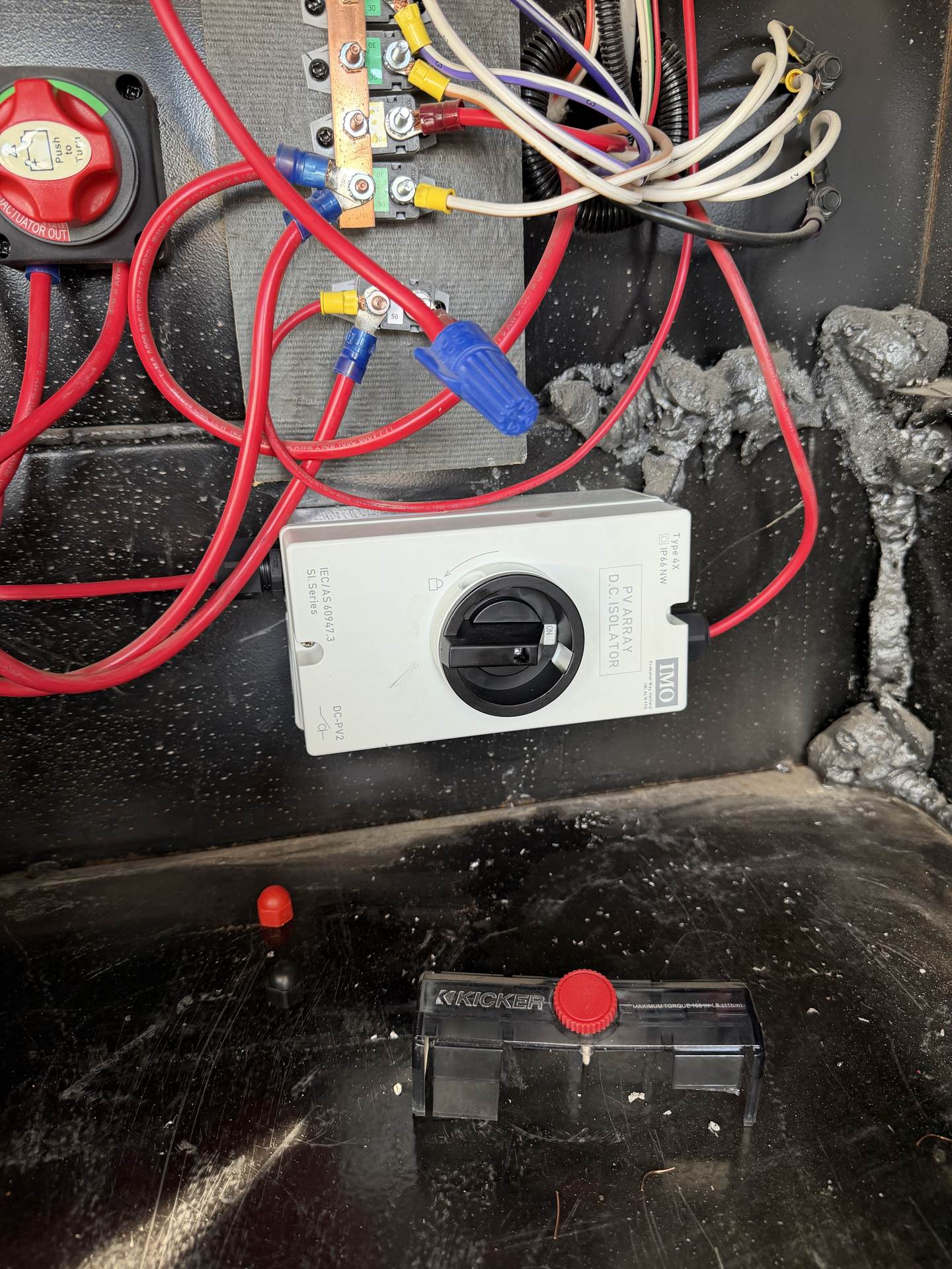 Newly installed RV DC isolator and battery disconnect switch with fresh red cabling, fuse block, and busbar in a wiring bay