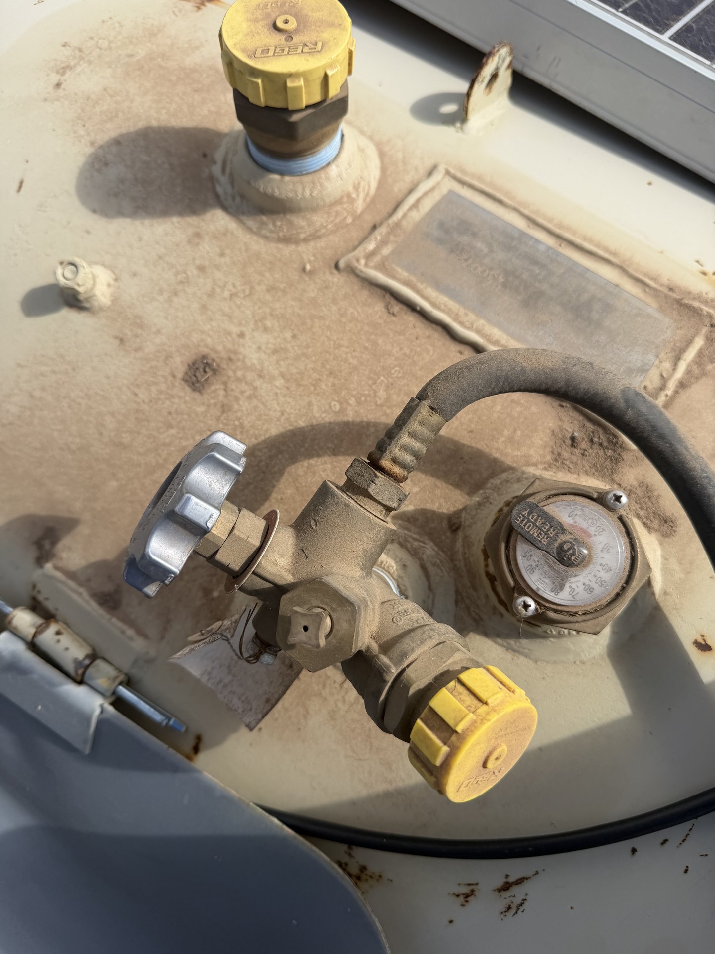 RV propane tank valve assembly with regulator, hose, and gauge inspected during a regulator replacement