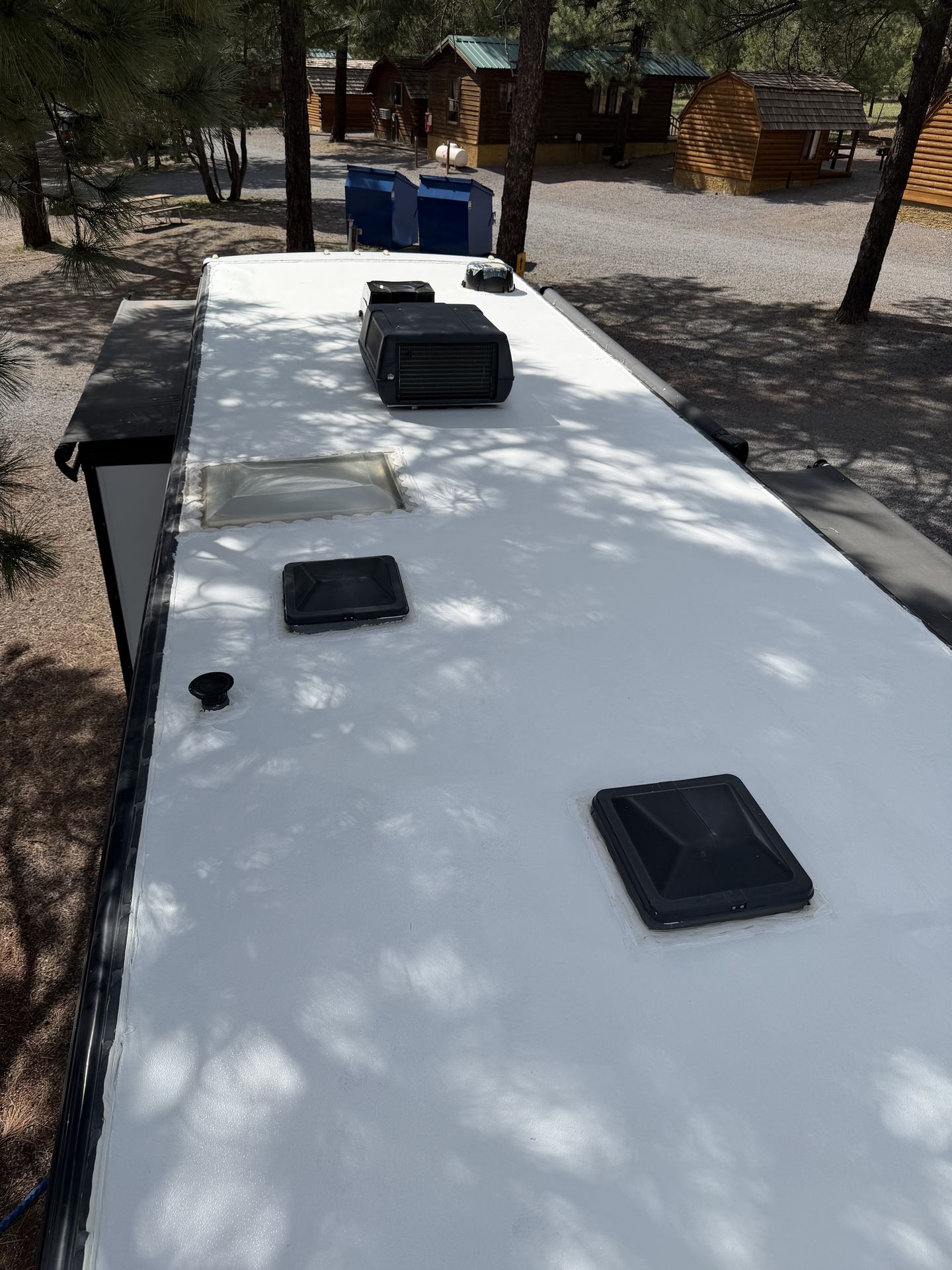Fresh self-leveling sealant applied along a seam and vent flange on an RV roof