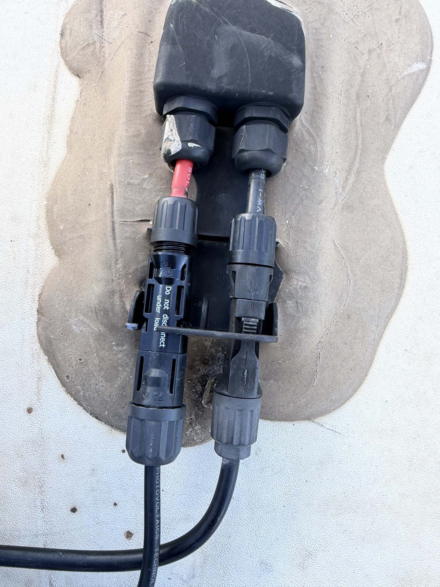 Solar panel junction box and MC4 connectors sealed to an RV roof with fresh lap sealant around the wiring penetration