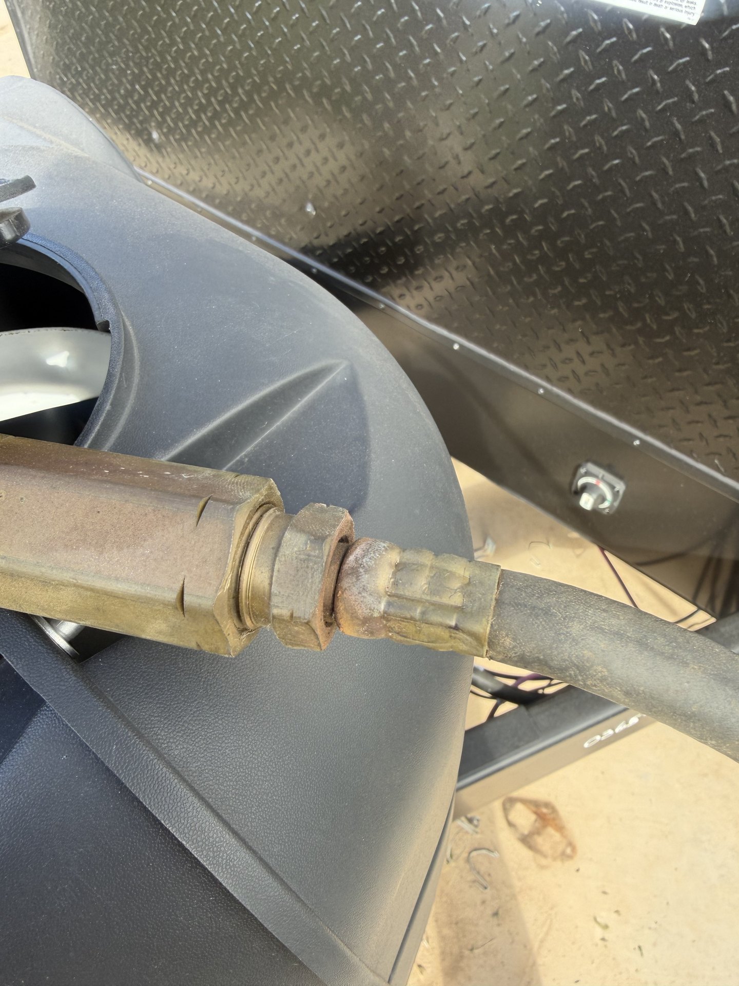 Brass propane fitting and rubber LP hose connection at an RV tank compartment being replaced