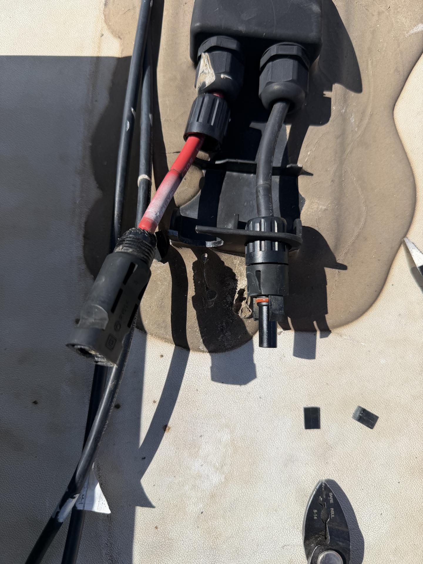 New MC4 connectors being crimped onto solar panel wiring on an RV roof with stripping pliers alongside