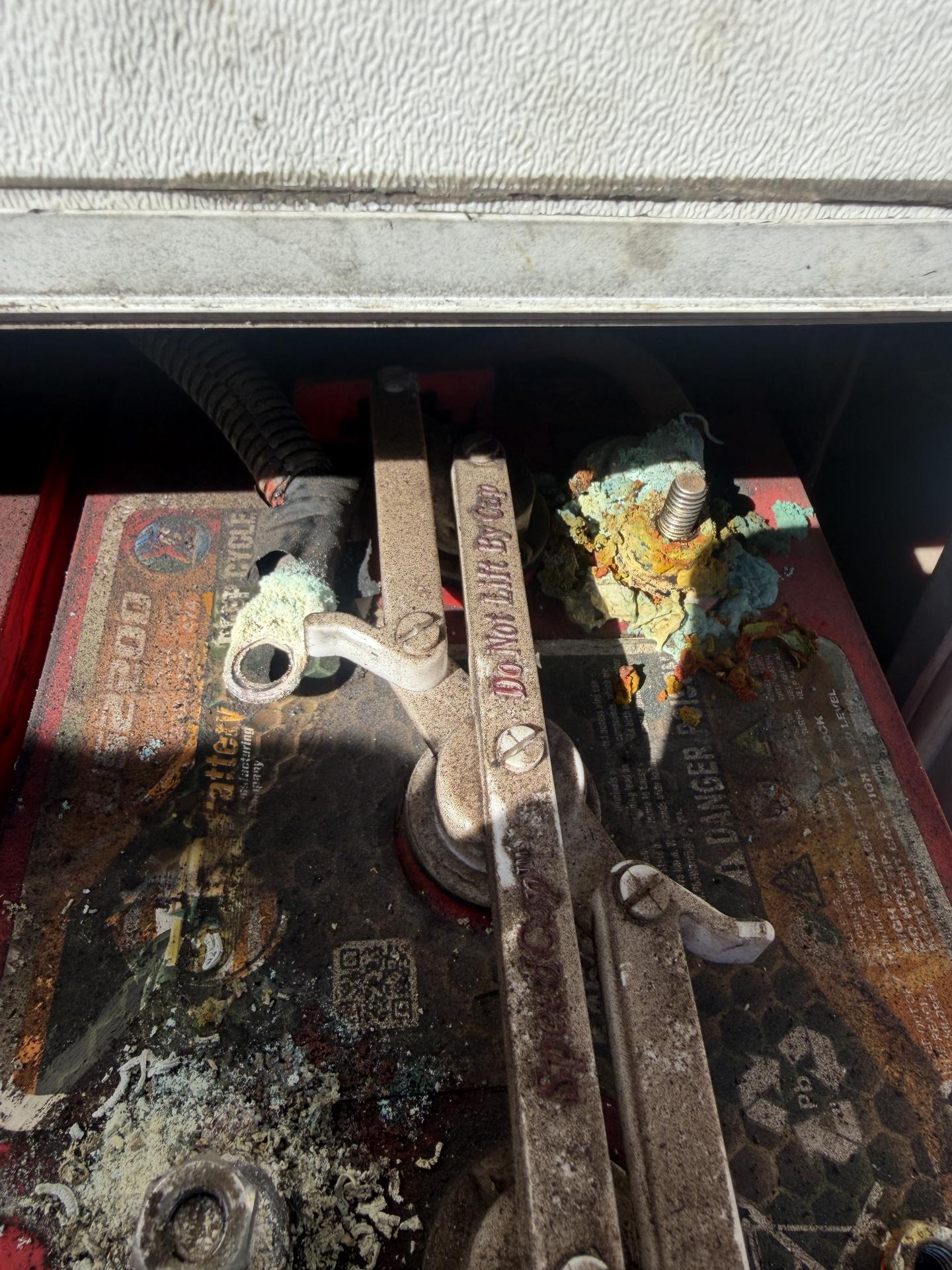 Heavily corroded RV house battery terminals and cable ends inside an open battery compartment during a mobile inspection in Northern Arizona